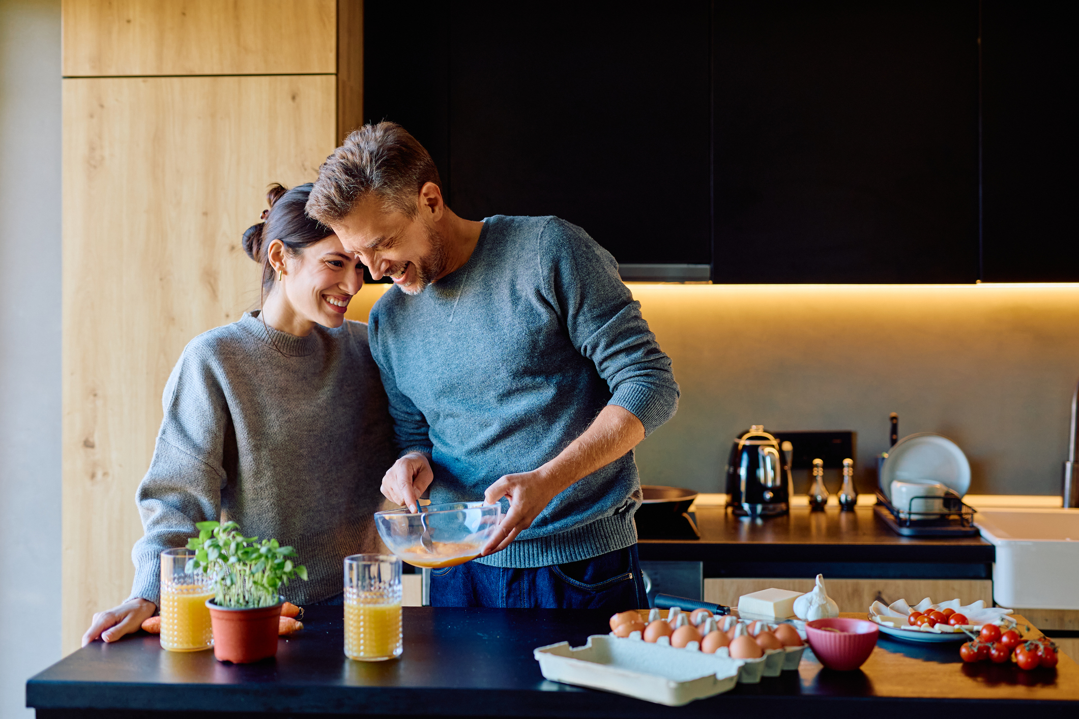 Happy couple cooking breakfast together in kitchen